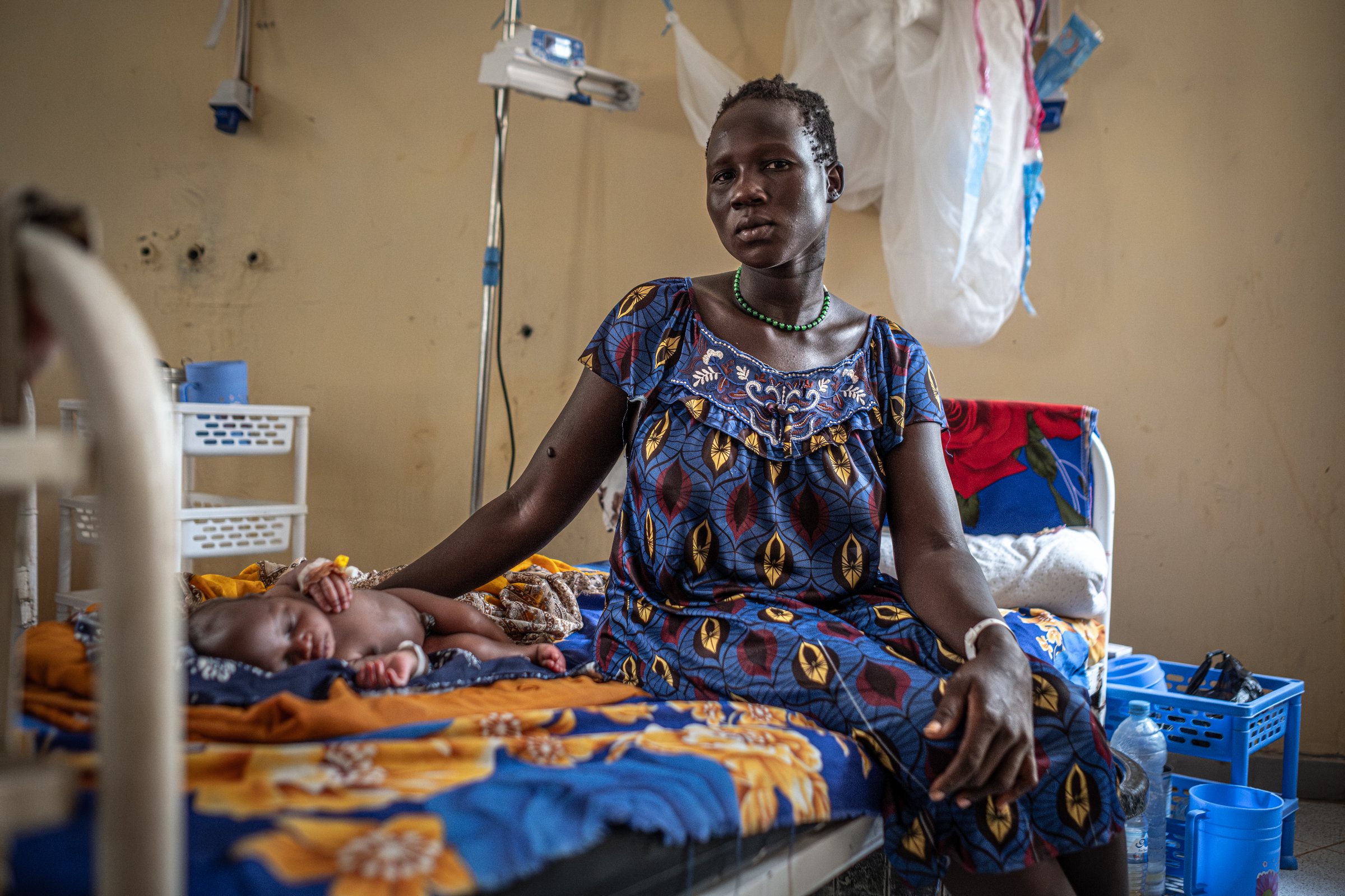 Dans une autre salle de l'hôpital, Nyekal Nuok veille sa petite fille née avec un spina-bifida quelques jours plus tôt. Elle aussi est originaire de Rotriak, localité située au nord de l'Unity Oilfield. État d'Unité, Soudan du Sud, mars 2026.