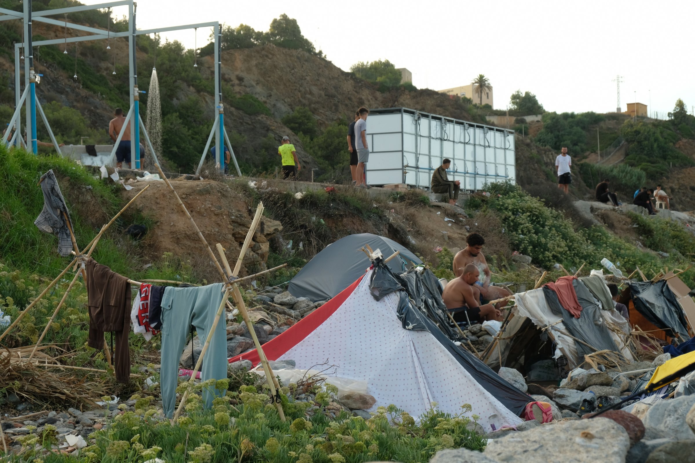 À Ceuta, sur la plage du Trampolìne, des migrants vivent dans un campement informel installé sur les rochers, à proximité de douches en plein air.