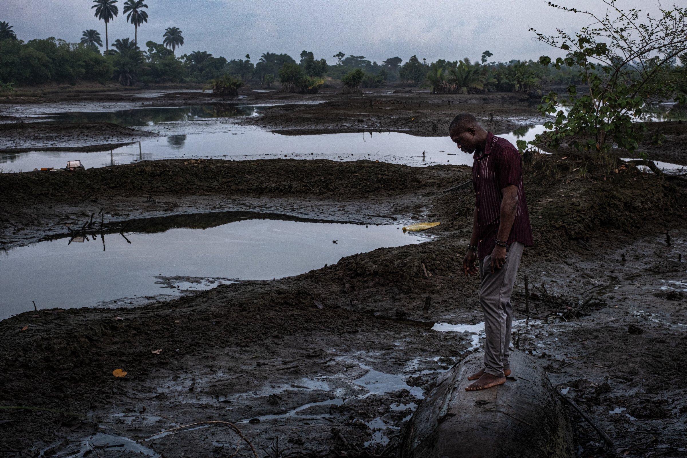 Un pêcheur contemple le sol contaminé à Gio, avec en arrière-plan le paysage du delta du Niger entièrement pollué par les marées noires. En Ogoniland, Rivers State, Nigeria.