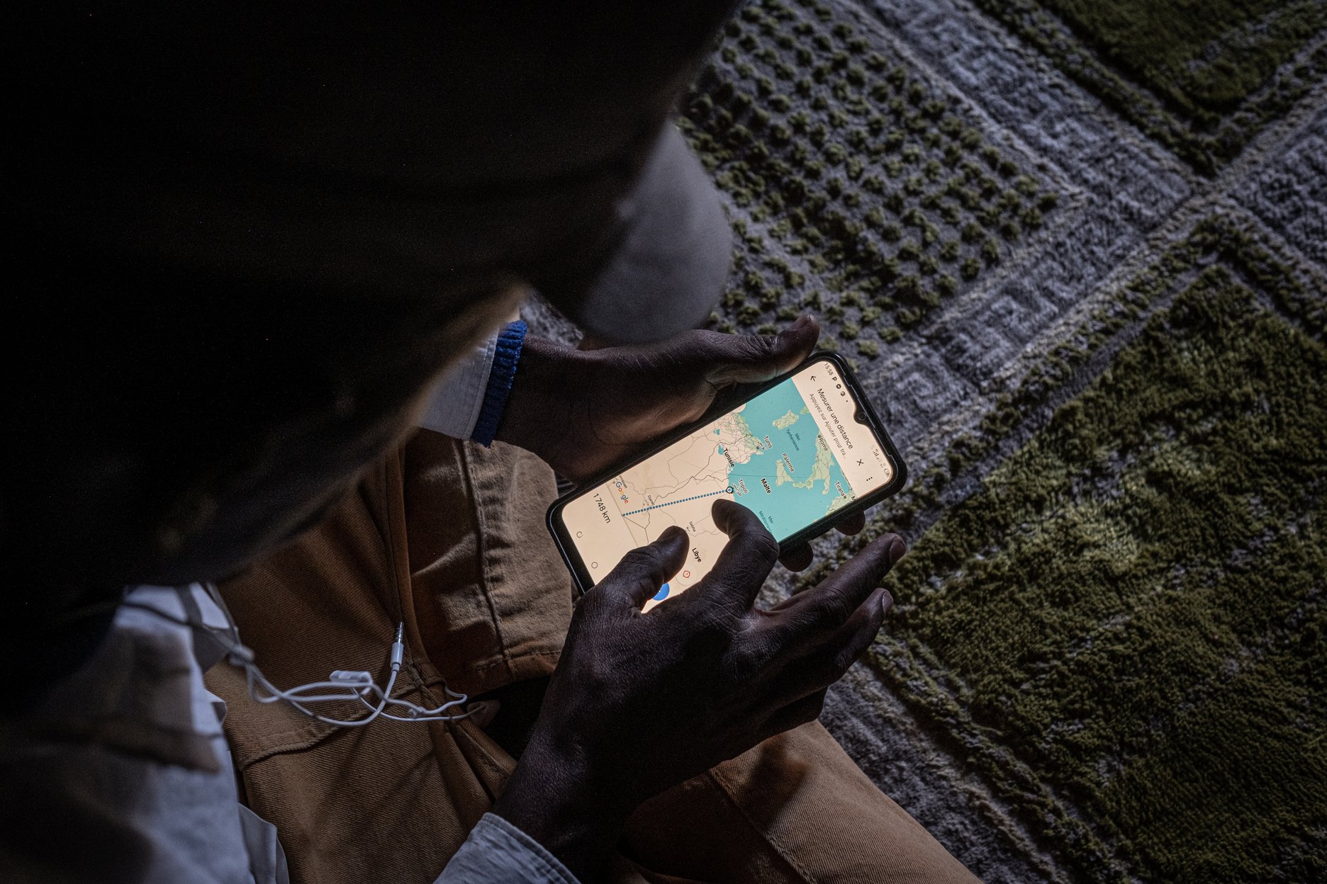 Ousmane, un Guinéen de 25 ans, montre la distance entre Agadez et Tripoli, en Libye. La traversée du désert est l'une des plus dangereuses au monde.