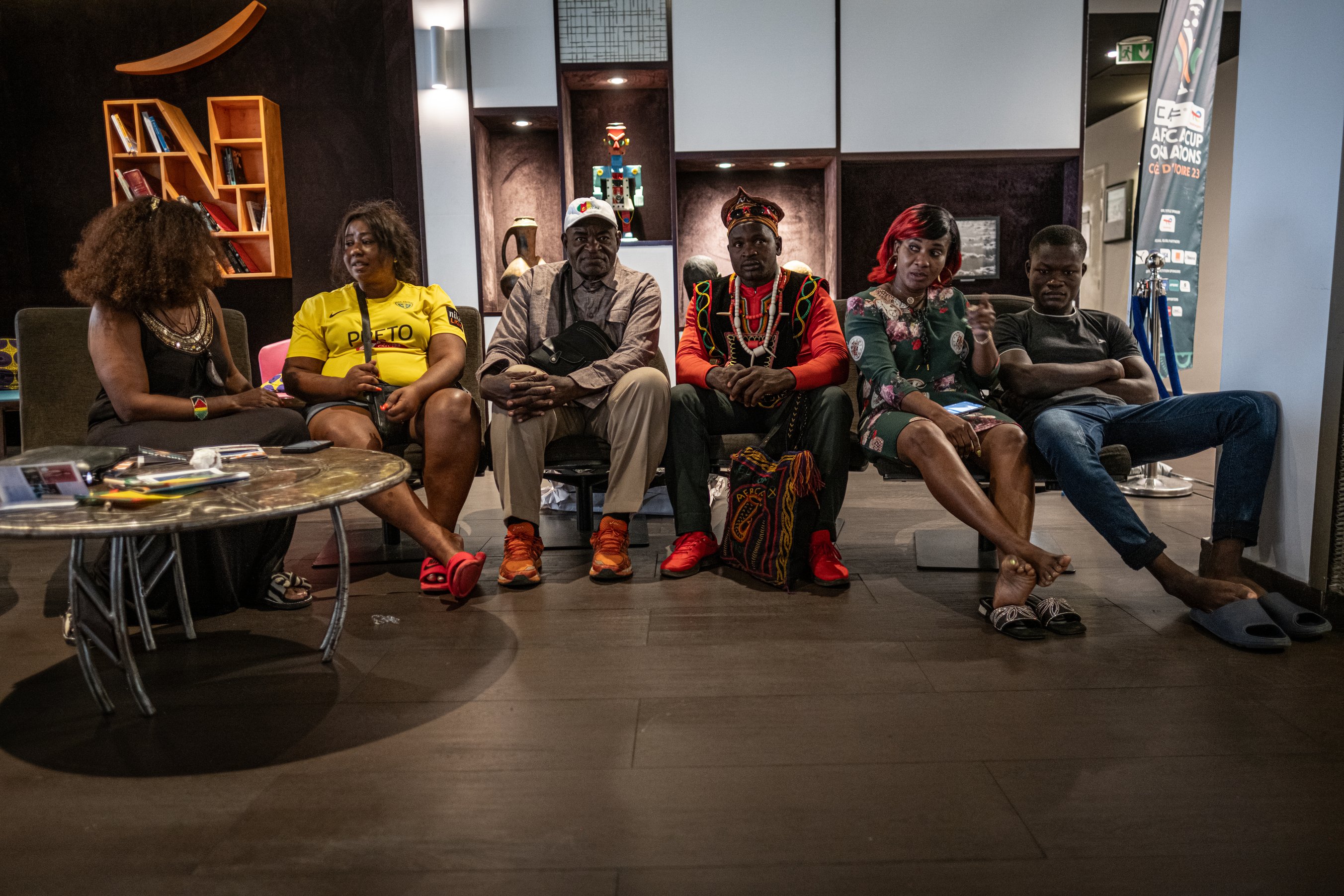 À la réception de l'hôtel Novotel d'Abidjan, le célèbre Ngando Pickett attend les joueurs et les membres de la fédération camerounaise. Lui et les autres supporters doivent demander des fonds pour financer le voyage de retour.