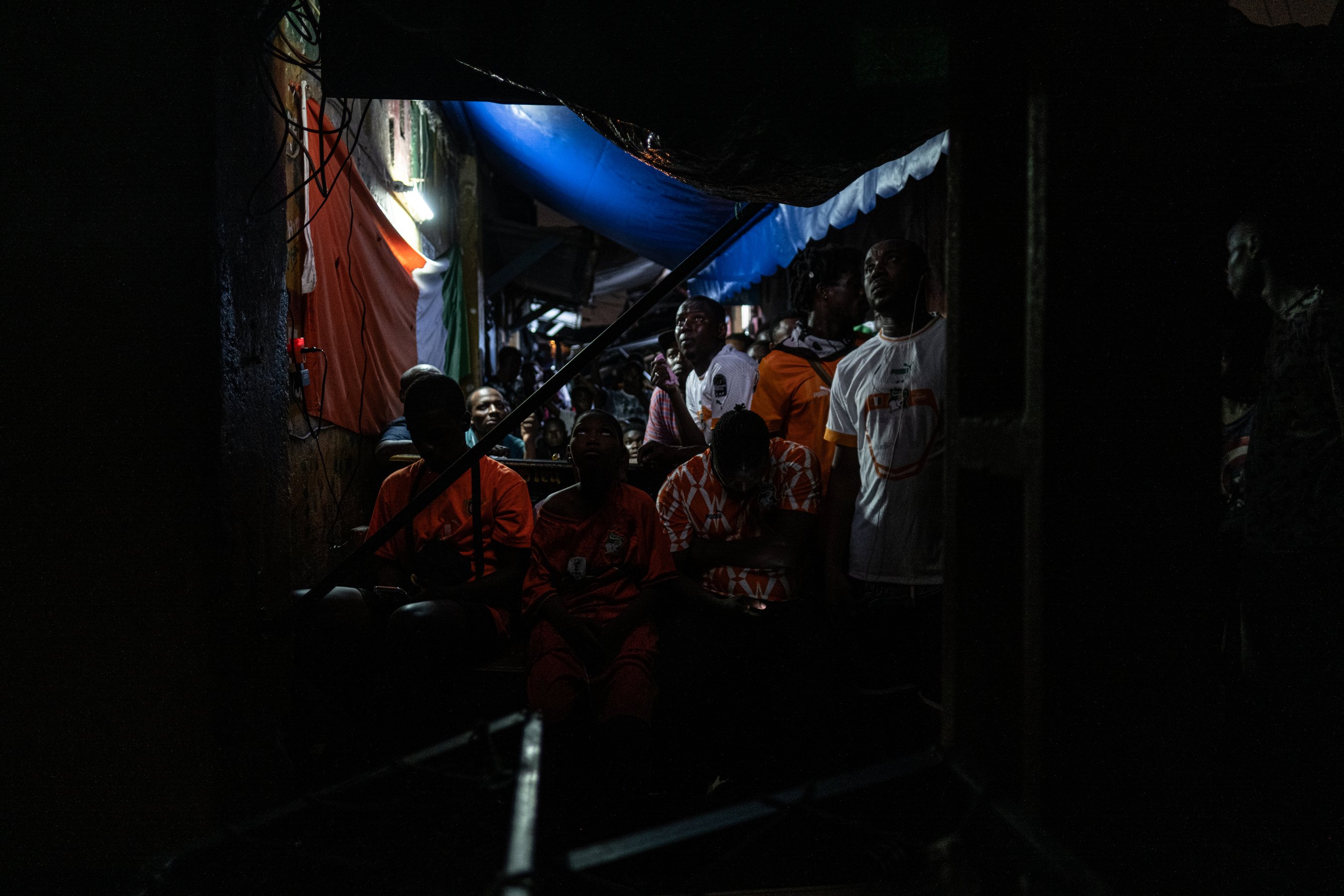 Des supporters ivoiriens regardent un match à la télé dans une ruelle du quartier de Cocody, à Abidjan.