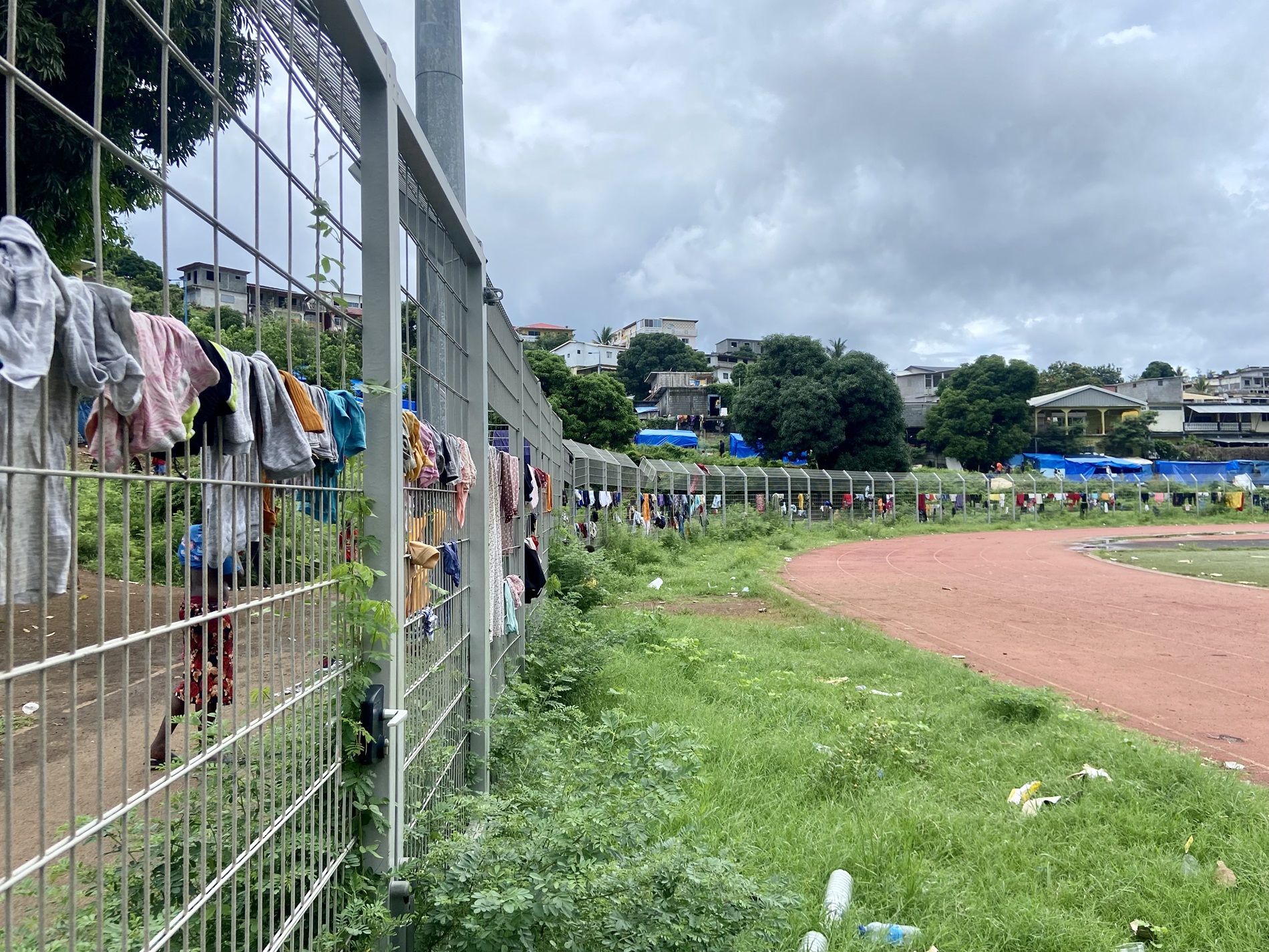 Vêtements d'exilé·es séchant sur les grilles du stade de Cavani, à Mamoudzou (8 janvier 2024).