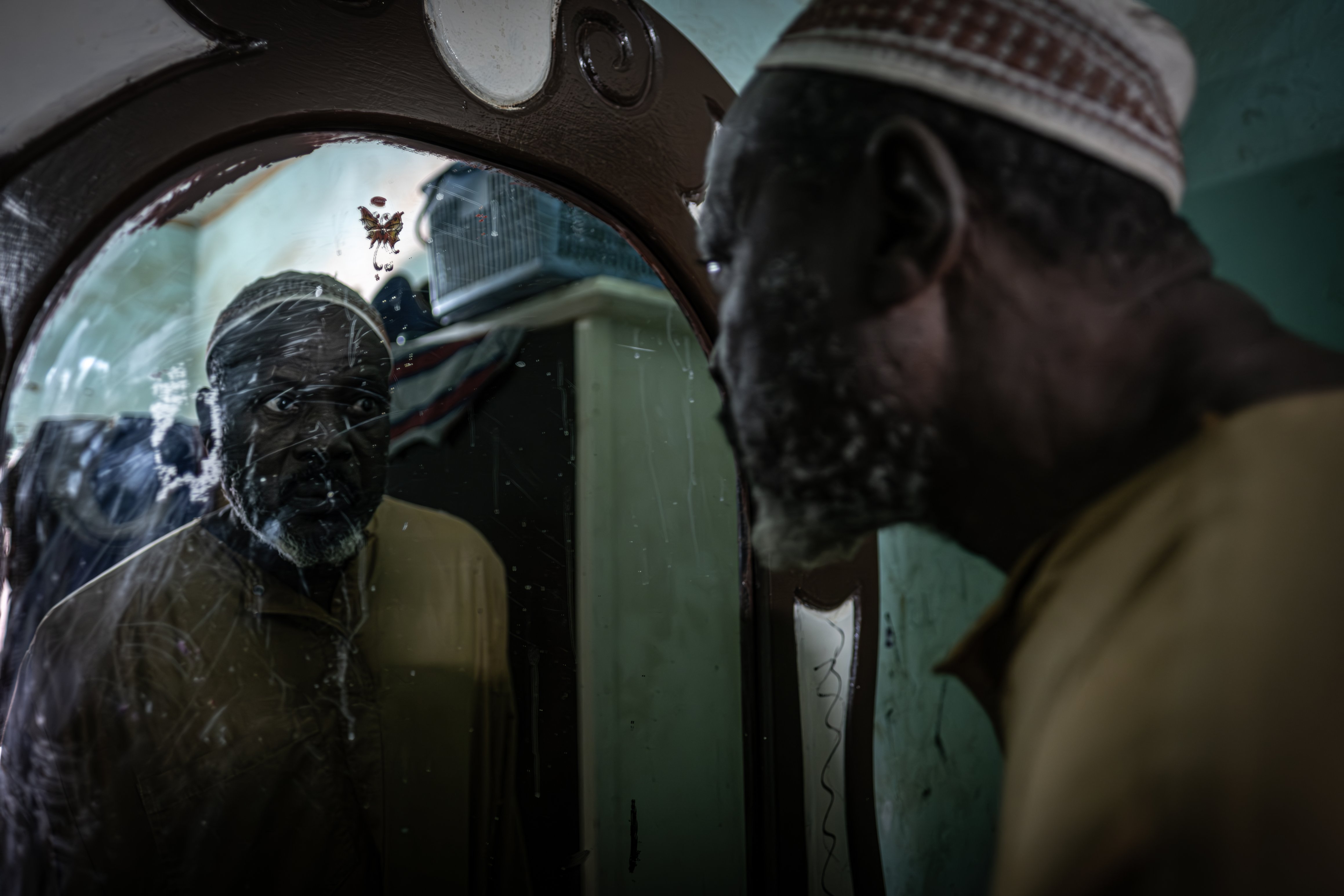 Issaka Alzouma, qui a travaillé pour la Cominak pendant plus de trente-huit ans, se regarde dans le miroir de sa maison d'Akokan. Il souffre de plusieurs maux, dont probablement la maladie d'Alzheimer.