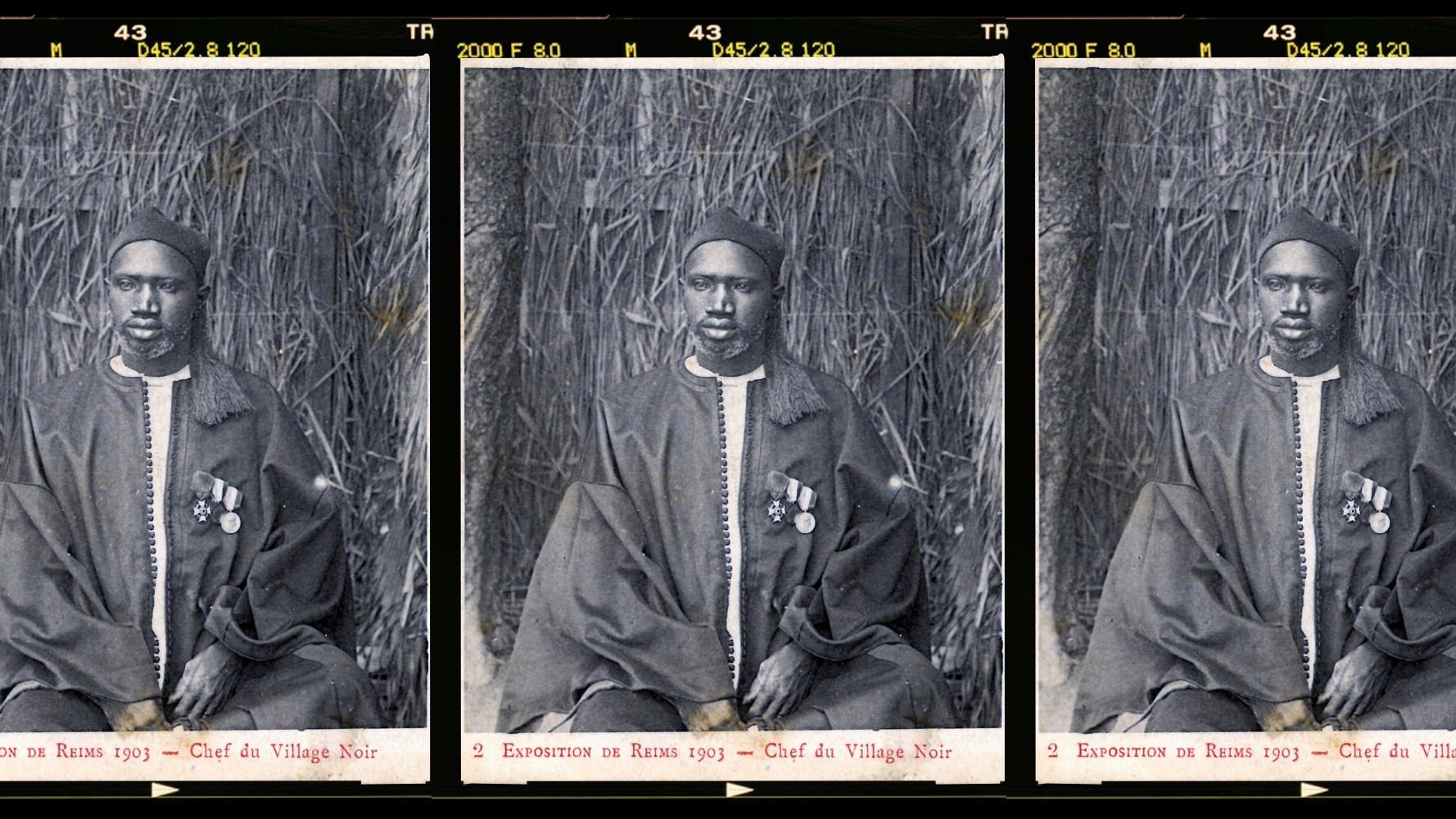 L'image présente trois portraits en noir et blanc d'un homme en costume traditionnel. Il est assis sur un fond de paille tressée qui évoque un environnement naturel. L'homme porte une tenue ample, probablement en textile sombre, et est décoré de plusieurs médailles accrochées à sa poitrine, ce qui suggère un statut élevé ou une reconnaissance. Son visage présente une expression solennelle et sérieuse. Les portraits sont disposés côte à côte, créant une composition symétrique. Cette image témoigne d'un moment historique, probablement lié à une exposition ou un événement marquant.