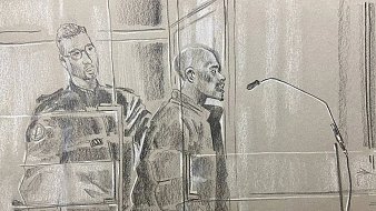 L'image représente une scène d'audience judiciaire. Au premier plan, on voit un homme debout, probablement un accusé, qui se tient derrière un panneau de séparation, exprimant une attitude sérieuse. Il est entouré par des éléments du tribunal, comme un microphone devant lui, indiquant qu'il pourrait s'exprimer. À sa gauche se trouve un policier en uniforme, affichant une posture attentive et vigilant. L'atmosphère de l'image est solennelle, reflétant le sérieux de la situation judiciaire. Les couleurs utilisées sont principalement des nuances de gris, et le style est esquissé, avec un rendu qui transmet les émotions et la tension de l'instant.