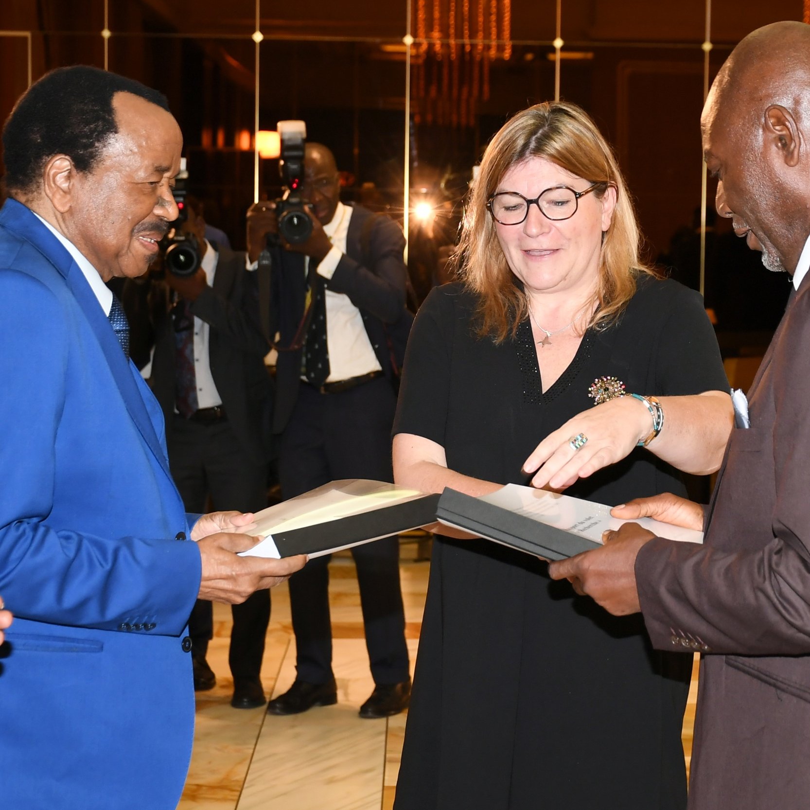 L'image présente des lettres en bois disposées sur une surface claire. Ces lettres forment trois mots : « PEOPLE », « REMEMBER » et « STORIES ». Chaque lettre est gravée de manière claire et se distingue par son esthétique monochrome, avec une finition lisse. L'ensemble évoque un message sur l'importance des histoires et de la mémoire collective.