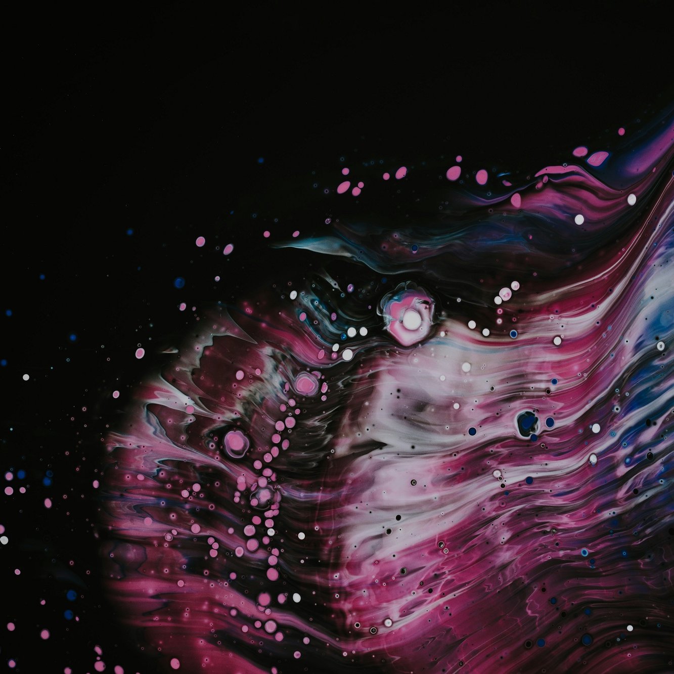 L'image présente une explosion de couleurs vibrantes sur un fond noir, évoquant un cosmos mystérieux. Des ondulations fluides rappellent des vagues, avec des nuances de bleu, de rose et de violet se mêlant harmonieusement. Des éclats de blanc, semblables à des étoiles dispersées, ajoutent une dimension de profondeur et de texture, créant une atmosphère dynamique et captivante. L'ensemble évoque un mouvement constant, presque euphorique, incitant à l'évasion et à la contemplation.