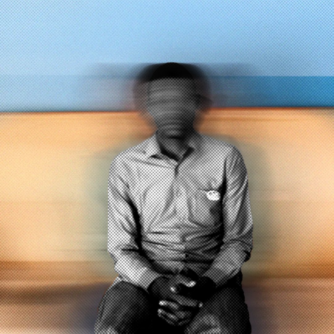 Cette image montre une personne assise sur un canapé. Le fond est flou, ce qui donne une impression de mouvement. La personne porte une chemise à rayures et a les mains posées sur ses genoux. L'atmosphère de l'image est douce grâce aux couleurs chaudes du canapé et aux nuances de bleu derrière. L'ensemble crée une sensation de calme, mais le flou ajoute une dimension de mystère.