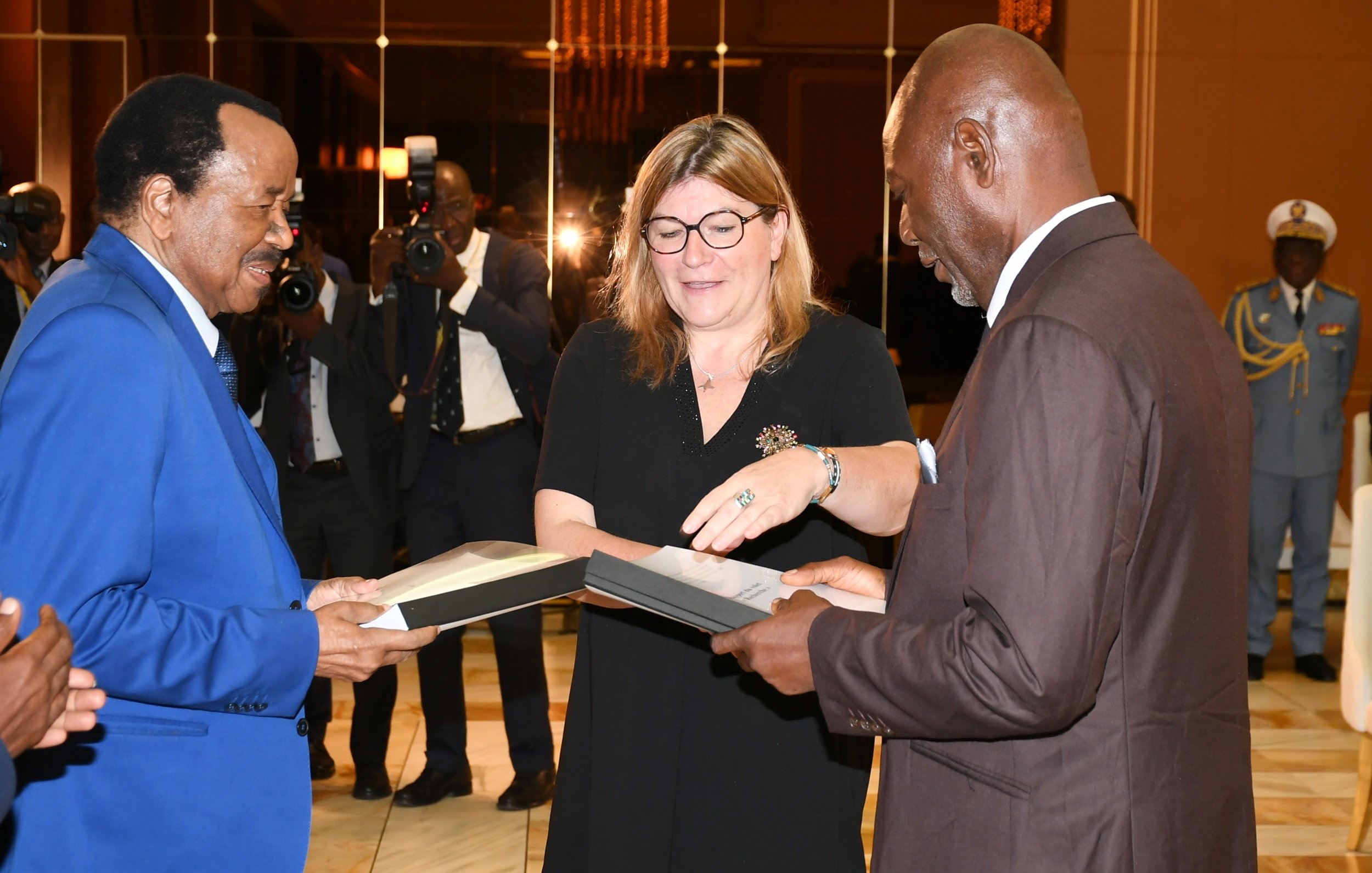 L'image présente des lettres en bois disposées sur une surface claire. Ces lettres forment trois mots : « PEOPLE », « REMEMBER » et « STORIES ». Chaque lettre est gravée de manière claire et se distingue par son esthétique monochrome, avec une finition lisse. L'ensemble évoque un message sur l'importance des histoires et de la mémoire collective.