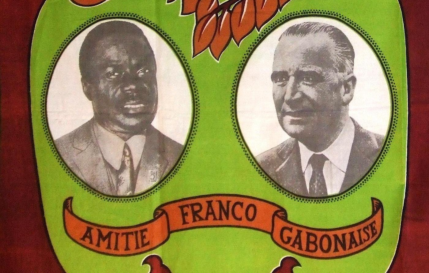 L'image présente un fond aux couleurs vives, dominé par des teintes vertes et marron. Au centre, deux portraits en noir et blanc sont encadrés. À gauche se trouve le portrait d'un homme à la peau noire, coiffé d'une chemise claire et affichant un regard sérieux. À droite, un homme à la peau claire, vêtu d'une chemise sombre, a une expression face à la caméra qui évoque la confiance. Entre les deux portraits, le mot "AMITIE" est inscrit en lettres majuscules, suivi de "FRANCO GABONAISE", soulignant un lien symbolique. Le motif de feuilles stylisées et d'ornements naturels en arrière-plan évoque un environnement tropical et chaleureux, symbolisant l'unité et la collaboration entre les cultures.