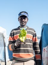 Lamine pose avec l'une des meilleures laitues du minuscule potager hérité de son frère, situé à côté de la tente où il dort.